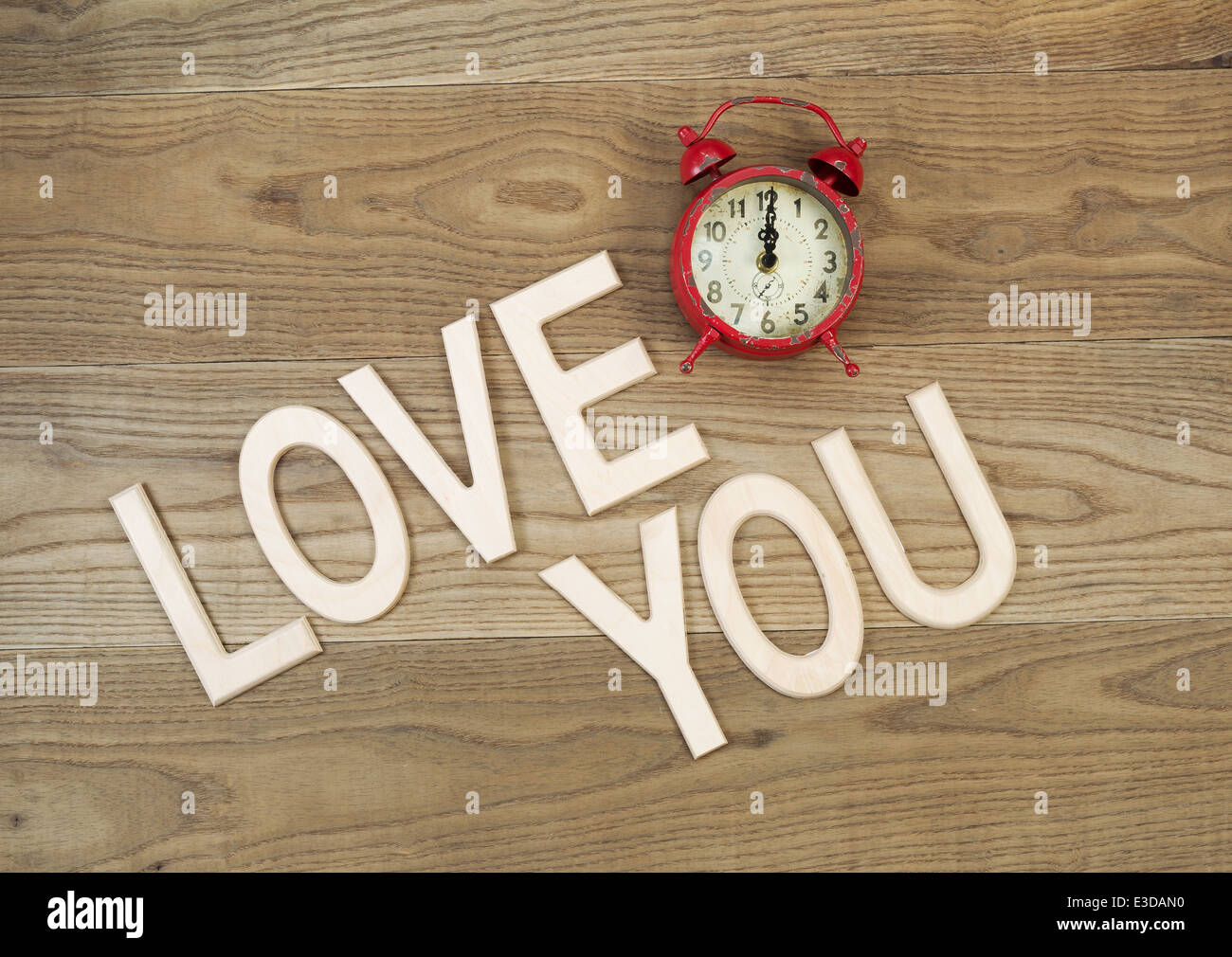Overhead view of an old table top alarm clock and large wooden letters spelling out Love You on rustic wood Stock Photo