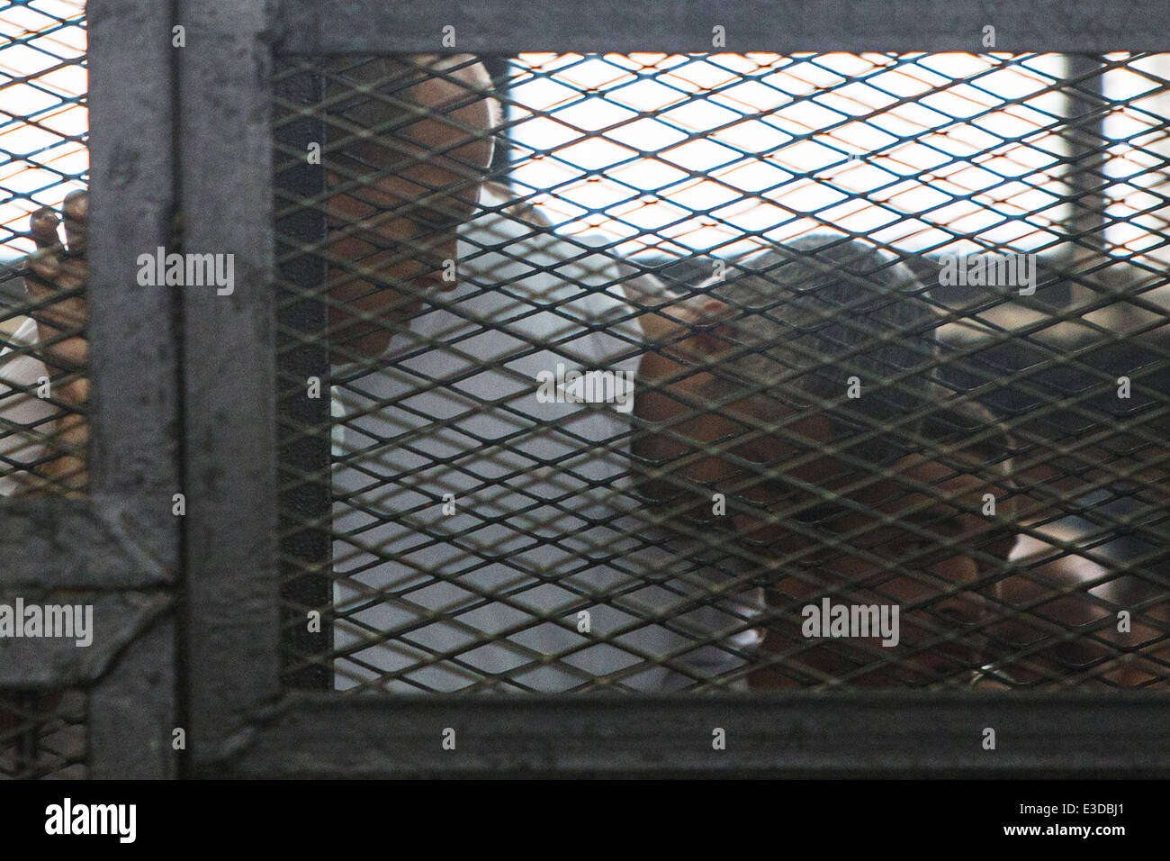 Cairo, Egypt. 23rd June, 2014. Egyptian-Canadian journalist Mohamed Fadel Fahmy (C) and Australian journalist Peter Greste (1st L) stand behind bars as they listen to the verdict at a court in Cairo, June 23, 2014. An Egyptian court sentenced three Al Jazeera journalists from seven to ten years over charges for aiding the currently blacklisted Muslim Brotherhood. Credit:  Cui Xinyu/Xinhua/Alamy Live News Stock Photo