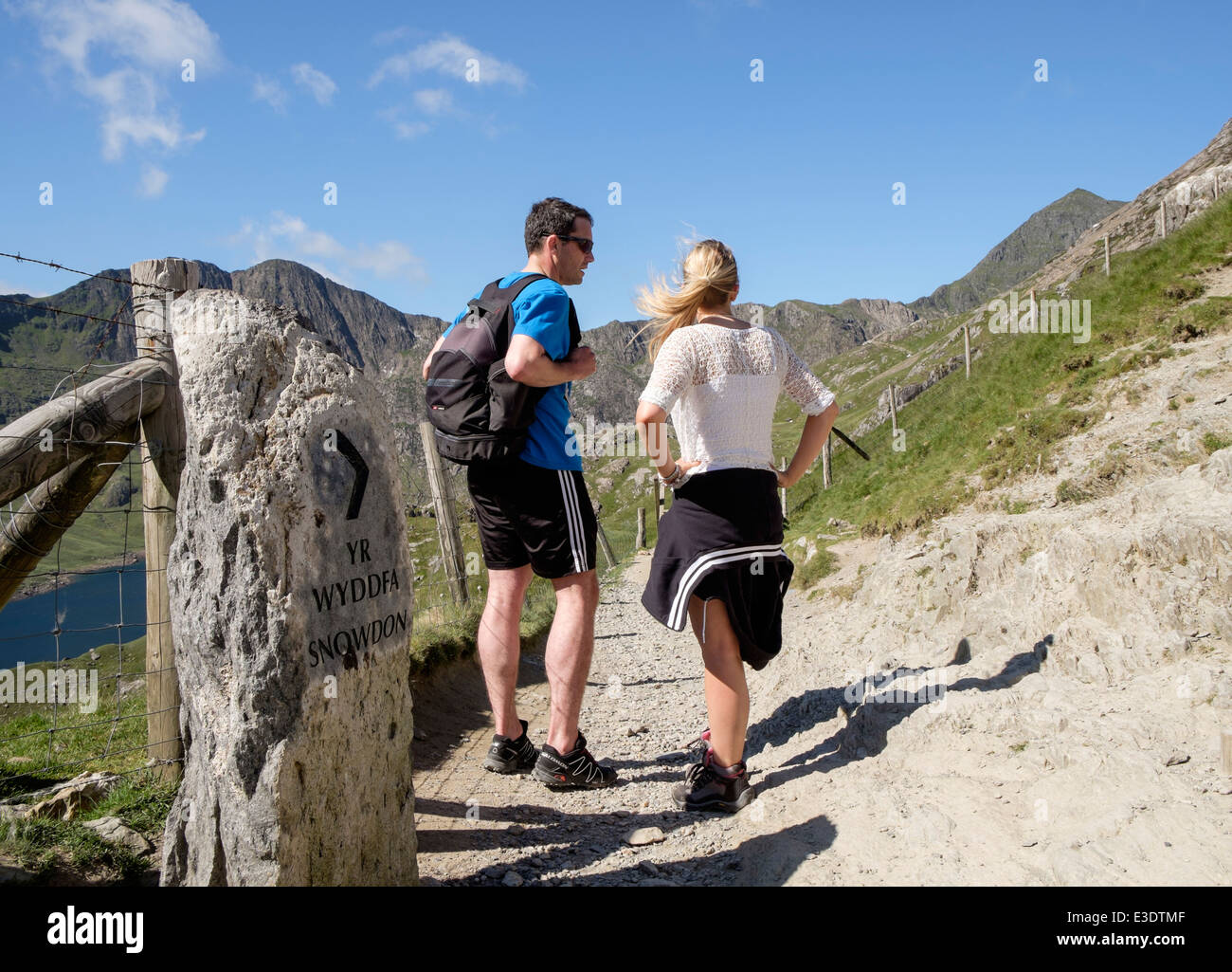 Ill-equipped walkers by direction sign on Pyg Track looking towards Mt Snowdon in mountains of Snowdonia North Wales UK Britain Stock Photo