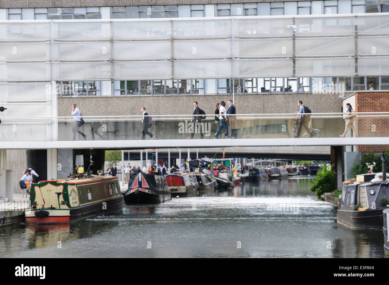 Workers rush to/from work while people in canal boats relax on the river at Paddington Basin Stock Photo