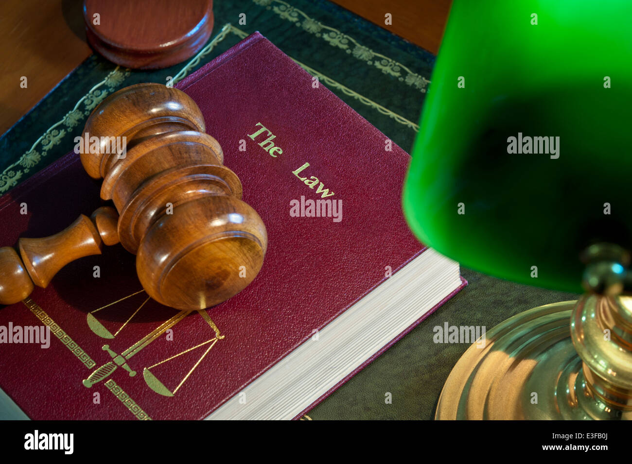 LAW COURTS SENTENCE Judges wooden gavel on 'The Law' book with scales of justice emblem illuminated by old desk lamp on leather bound bench desk Stock Photo