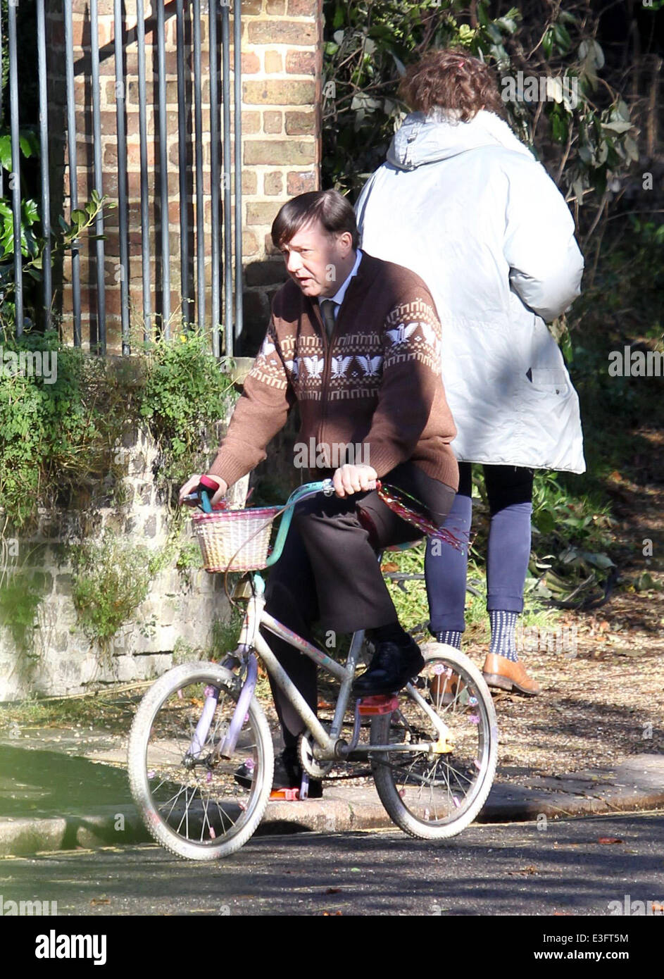 Ricky Gervais filming for the new Channel 4 TV series Derek in North London. Gervais body double is seen being filmed riding a girls bike chasing an undertakers van several times before