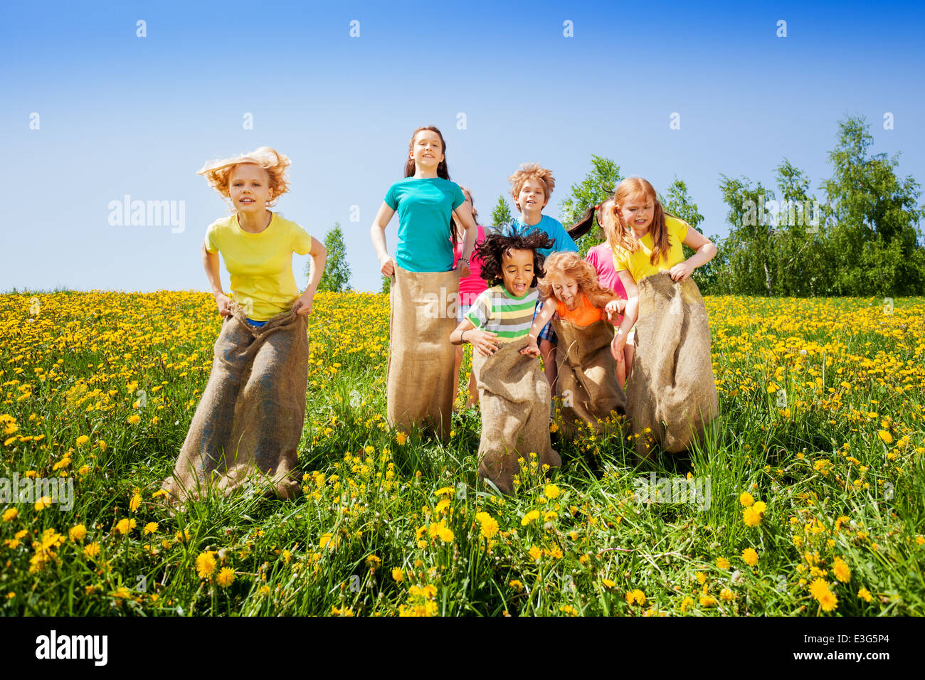 Happy kids jumping in sacks playing together Stock Photo