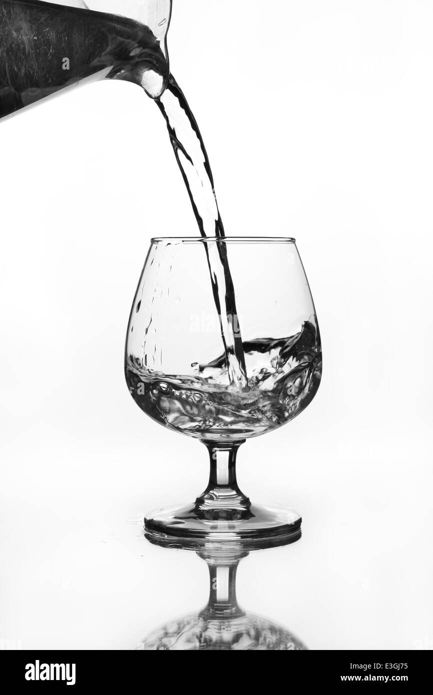 water jug pouring to wine glass with shadow (gray scale) Stock Photo