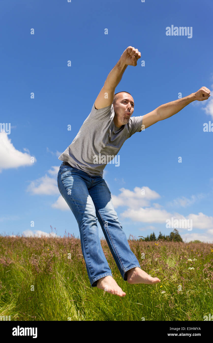 active adult is jumping in front of a blue sky Stock Photo