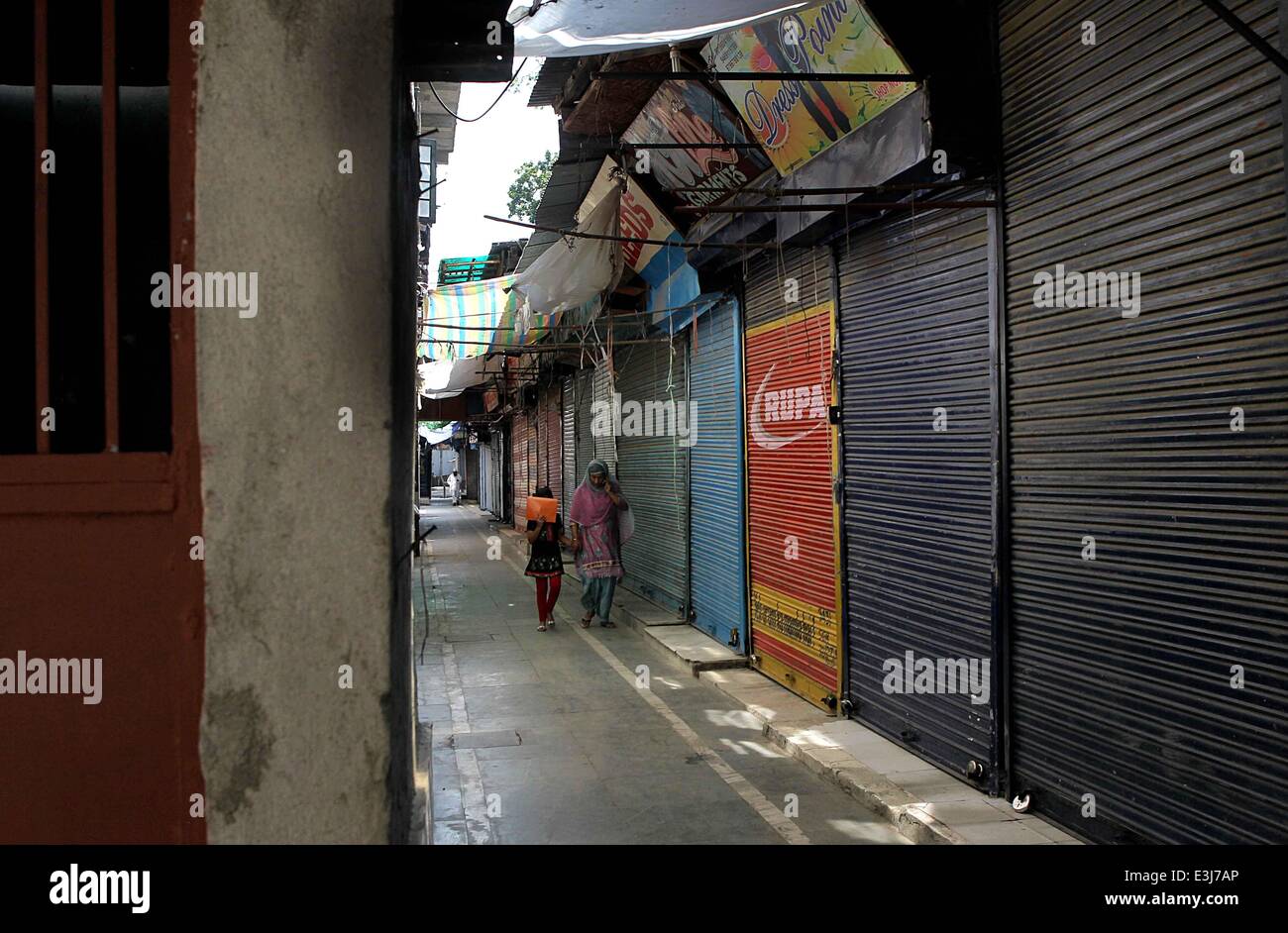(140624) -- SRINAGAR, June 24, 2014 (Xinhua) -- A Kashmiri woman walks along with her daughter through a closed market during a strike in Srinagar, the summer capital of Indian-controlled Kashmir, June 24, 2104. Normal life in Muslim majority areas of Indian-controlled Kashmir including Srinagar city was affected Tuesday due to a separatist shutdown. The shutdown call was given by region's Separatist group to protest the killing of a youth when Indian troops fired at protesters on Monday. The protests broke out at Krank Shivan in Sopore town, about 54 km northwest of Srinagar city following th Stock Photo