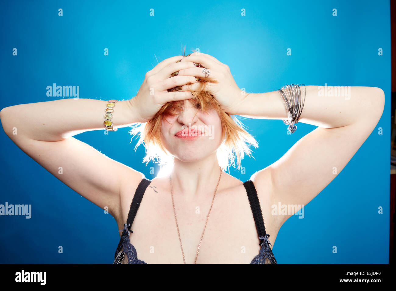 Young Woman with Hands on Head Grimacing Stock Photo