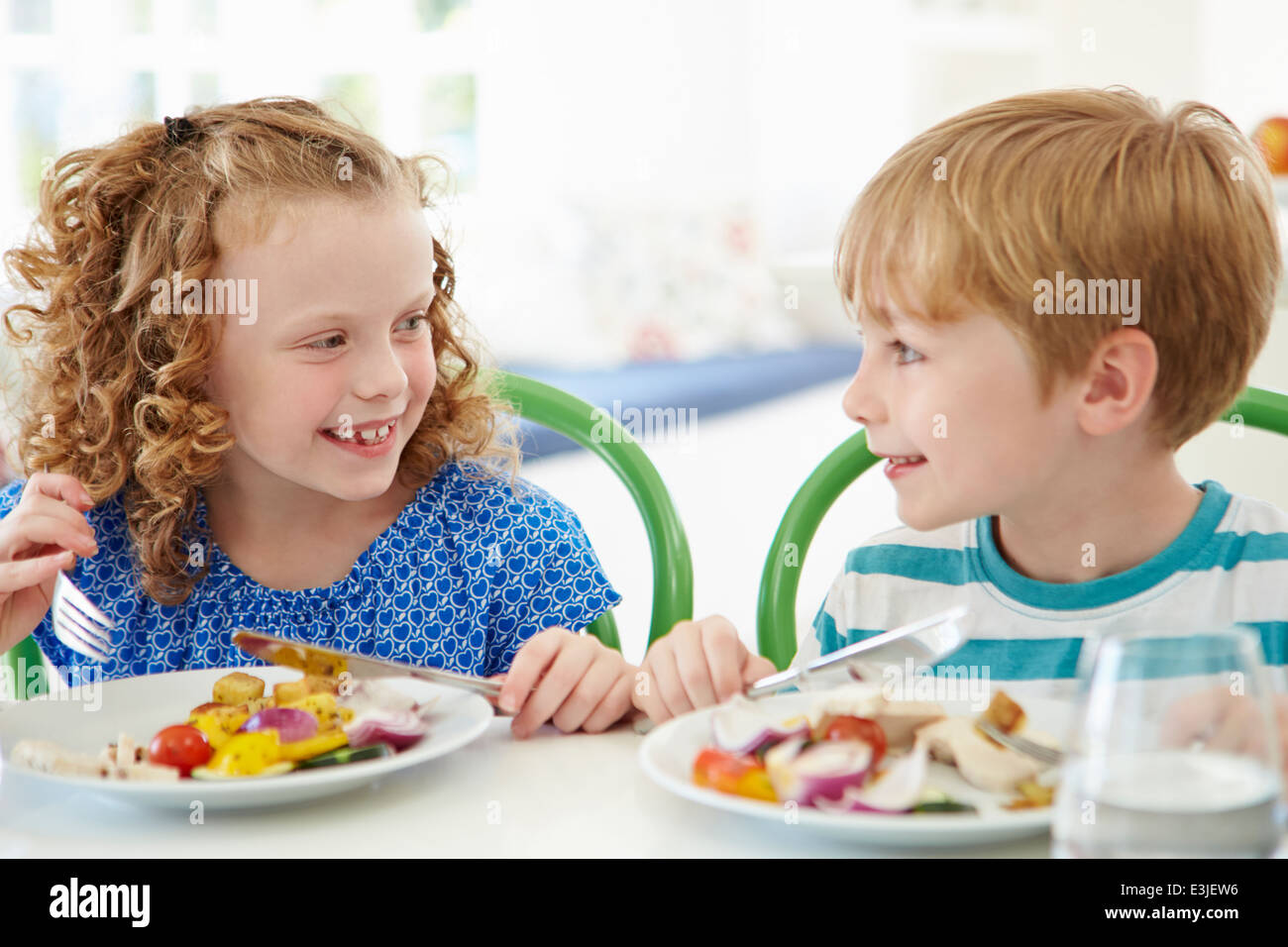 Two Children Eating Meal At Home Together Stock Photo