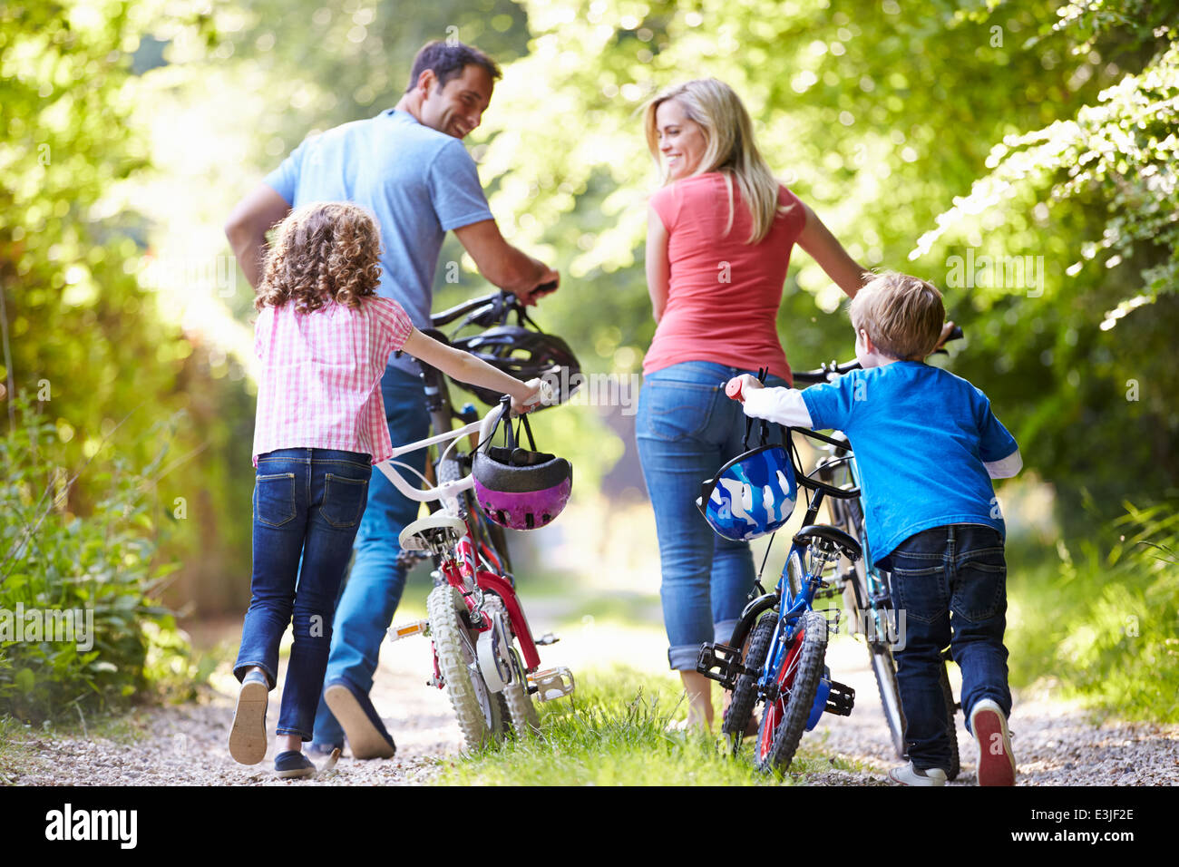 Family Pushing Bikes Along Country Track Stock Photo