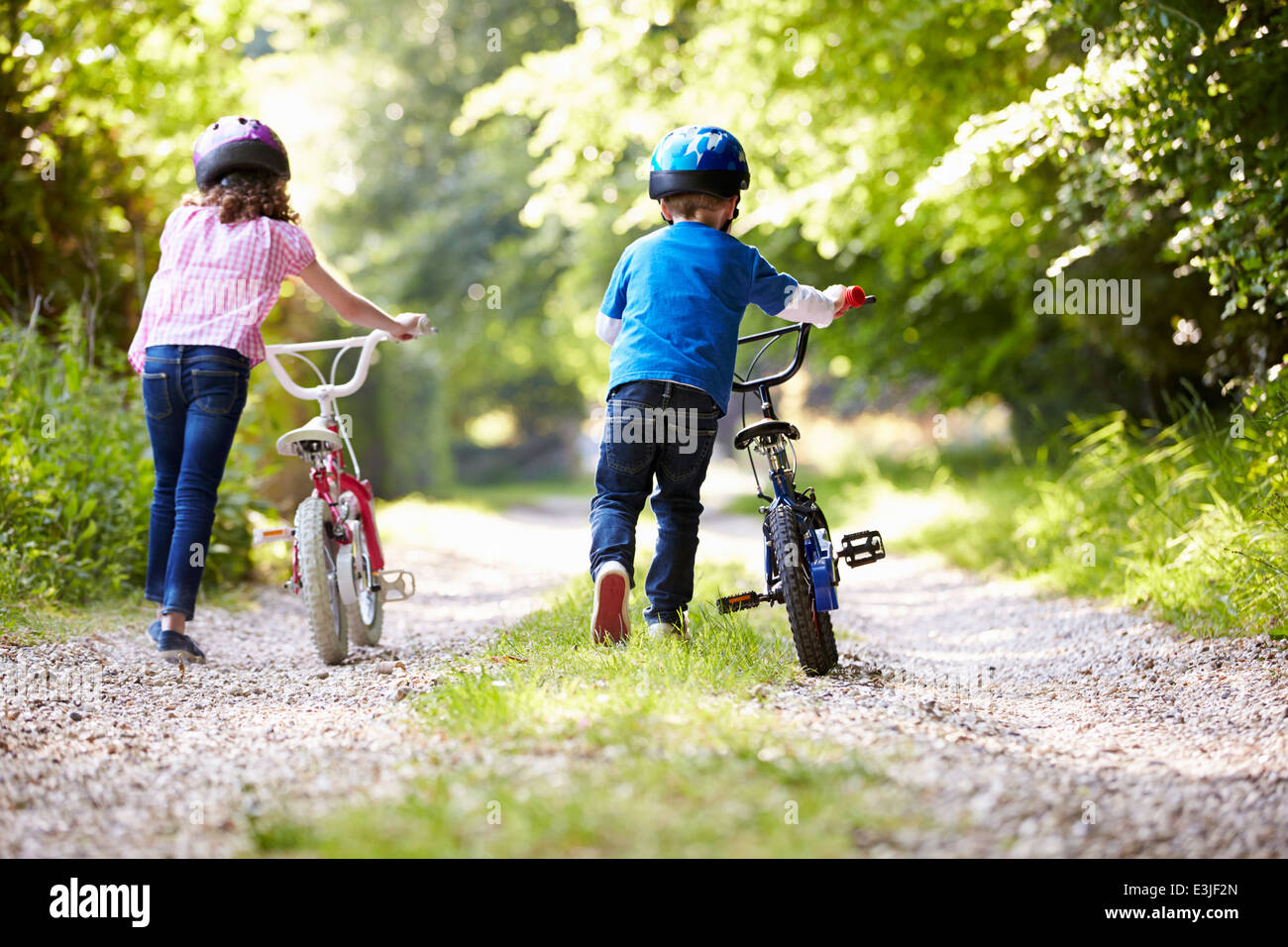 Two Children Pushing Bikes Along Country Track Stock Photo