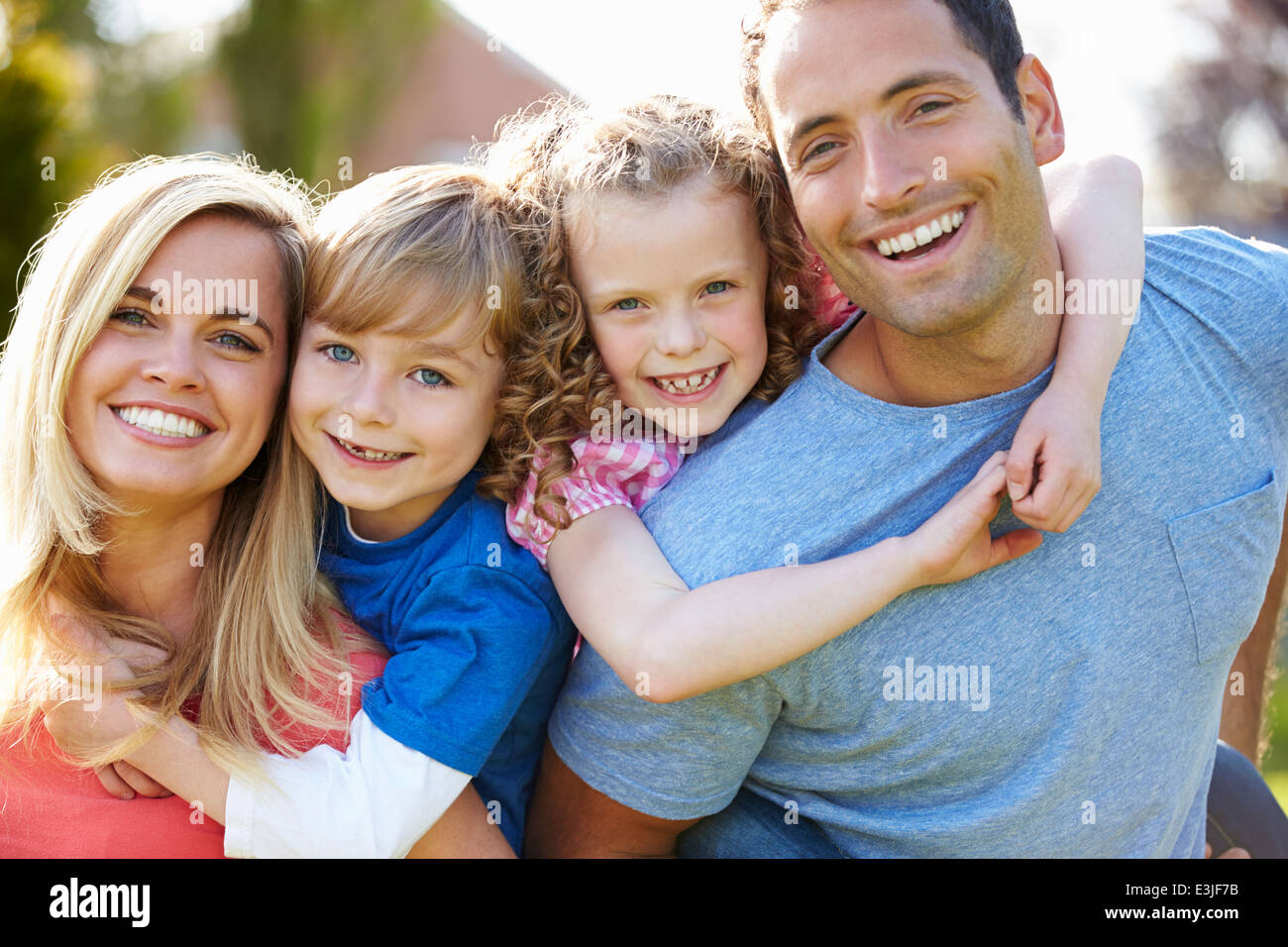 Parents Giving Children Piggyback Rides In Garden Stock Photo