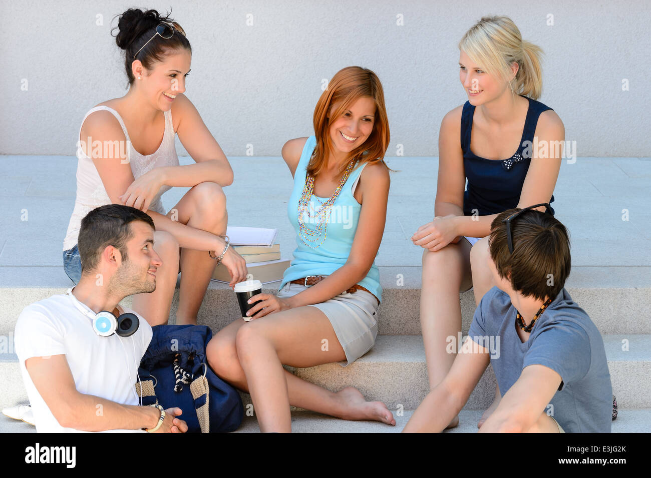 Students enjoying break sitting on school steps happy teenage friends Stock Photo