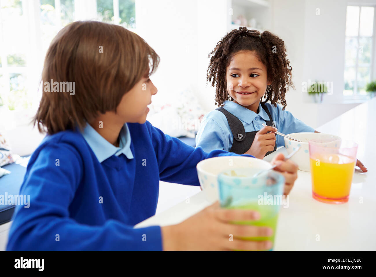 Two Children Having Breakfast Before School In Kitchen Stock Photo