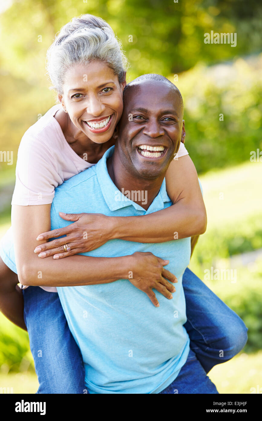 Mature Man Giving Woman Piggyback In Countryside Stock Photo