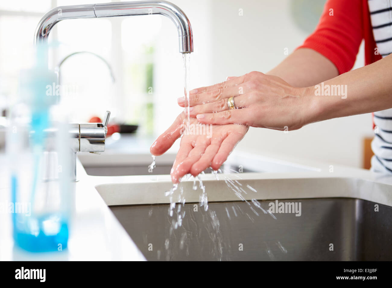 Close Up Of Woman Washing Hands In Kitchen Sink Stock Photo
