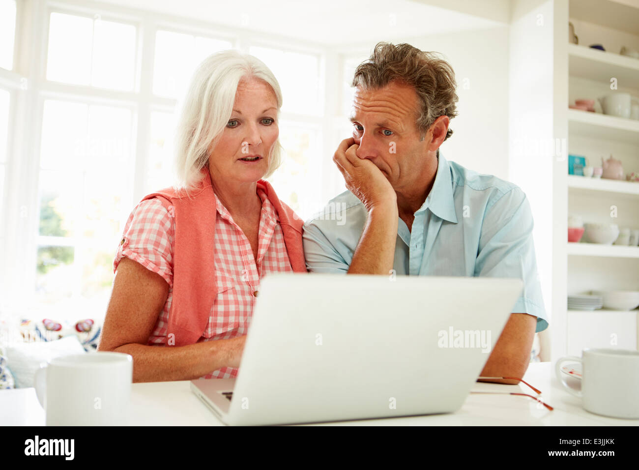 Worried Middle Aged Couple Looking At Laptop Stock Photo