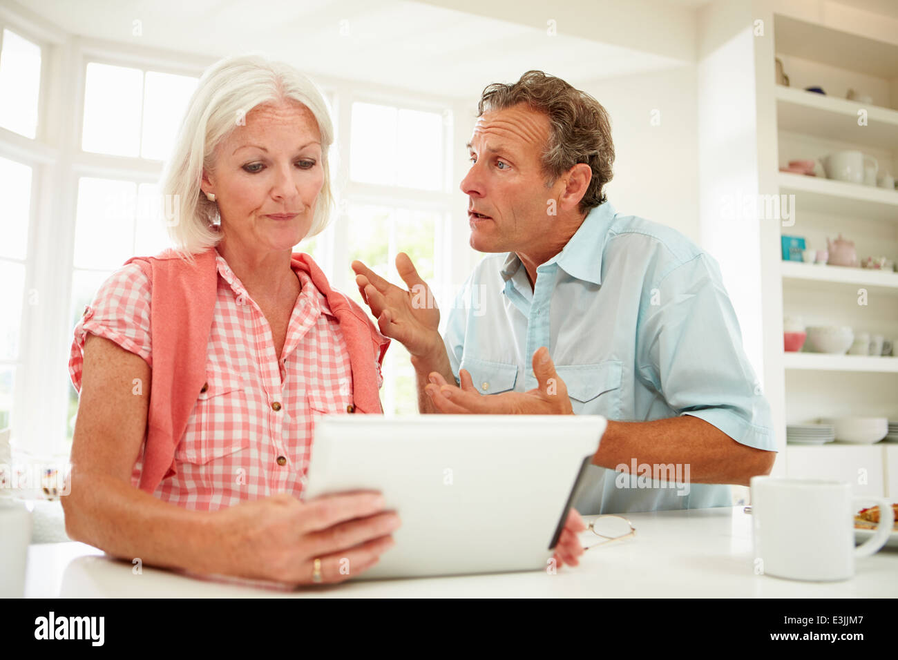 Worried Middle Aged Couple Looking At Digital Tablet Stock Photo