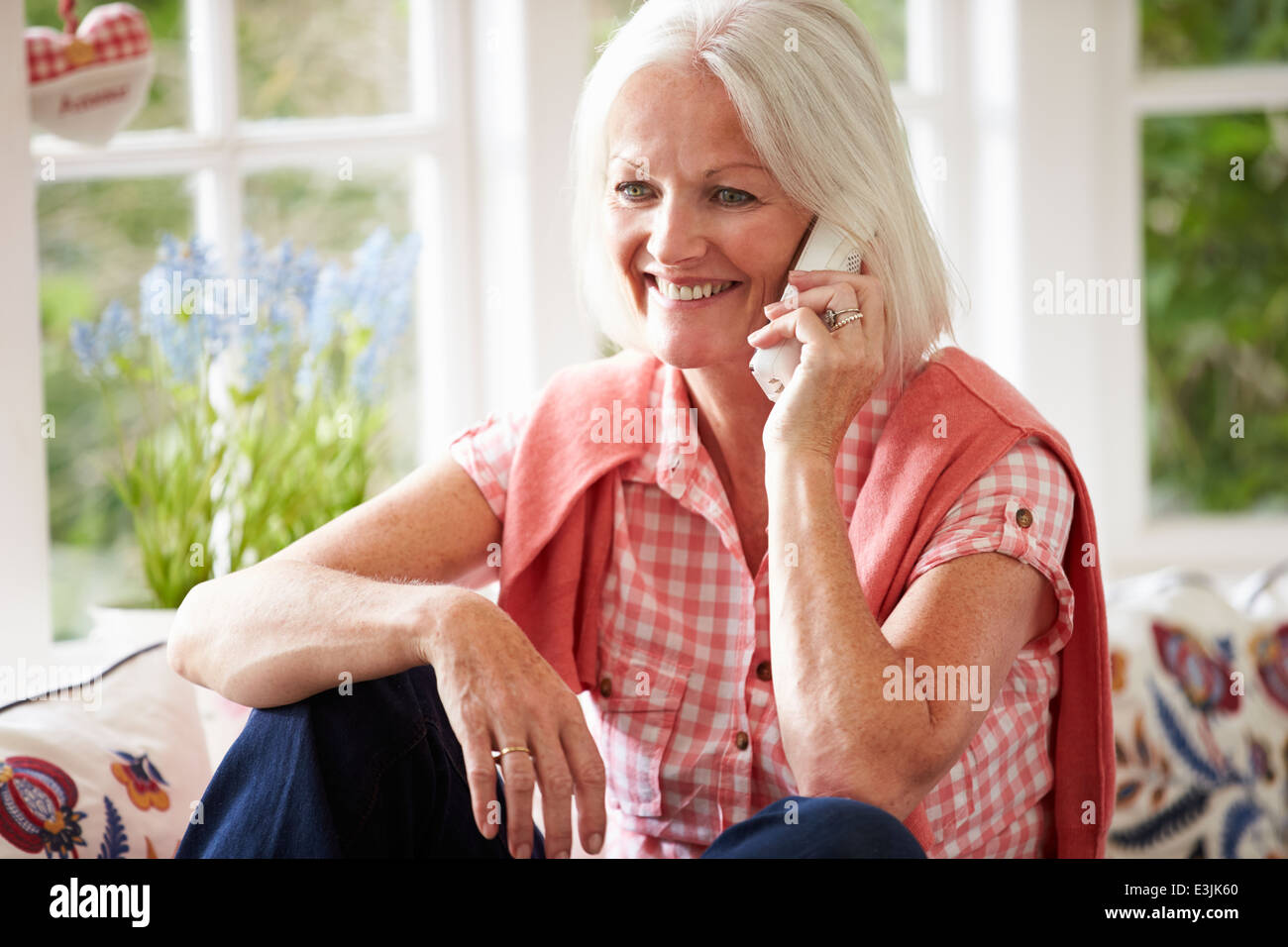 Middle Aged Woman At Home Talking On Phone Stock Photo