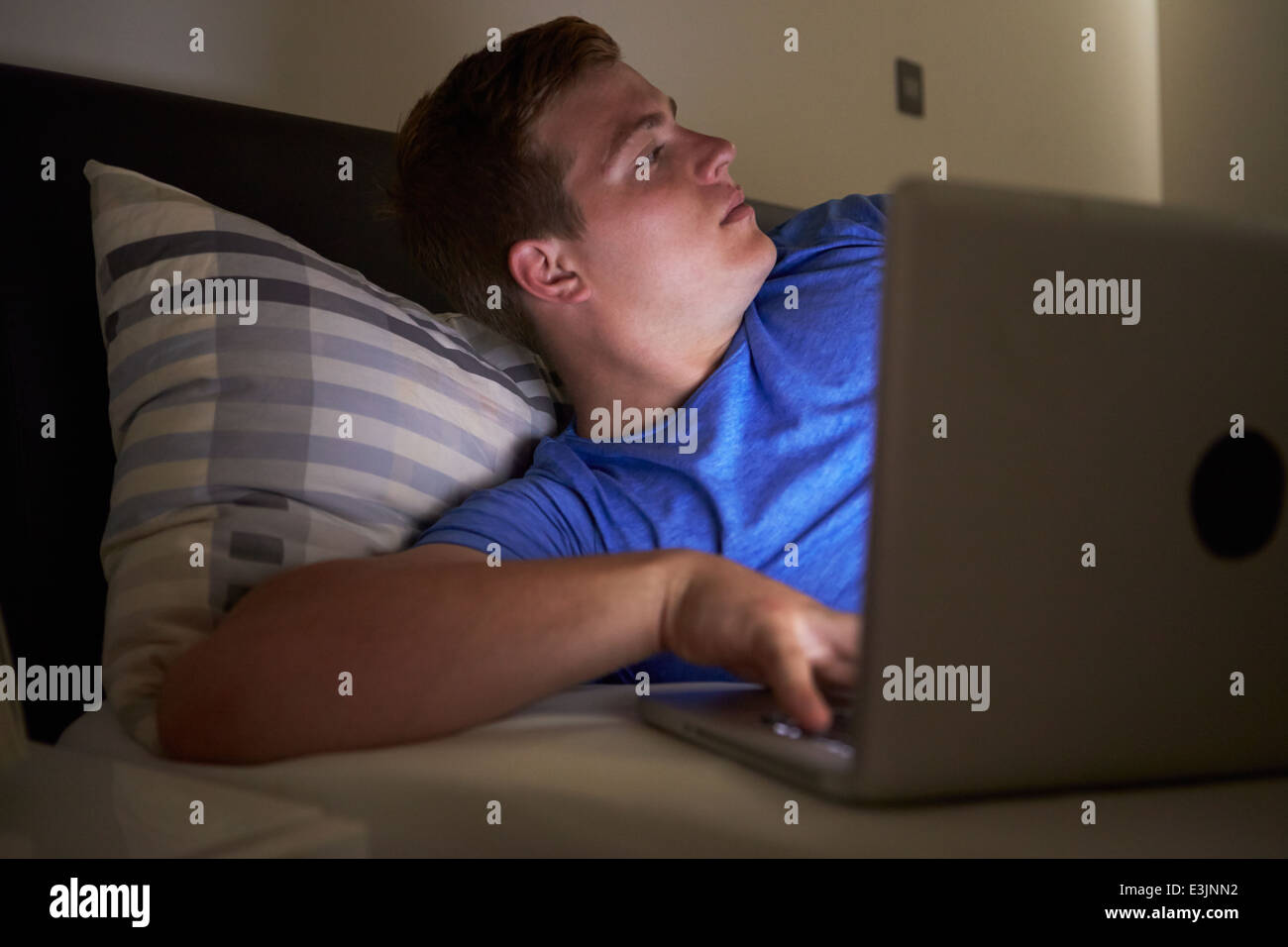 Worried Teenage Boy Using Laptop In Bed At Night Stock Photo - Alamy