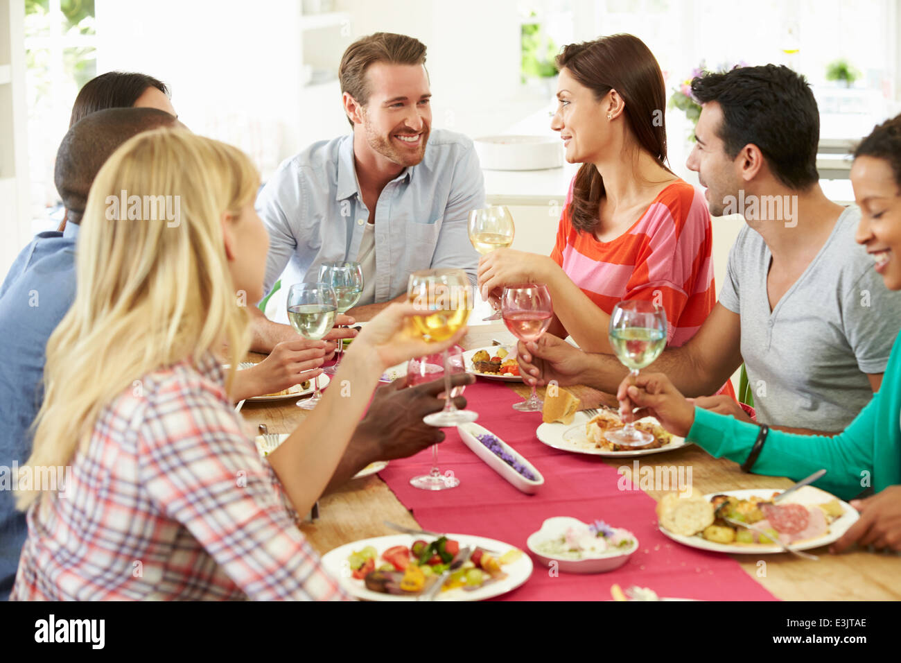 Group Of Friends Making Toast Around Table At Dinner Party Stock Photo