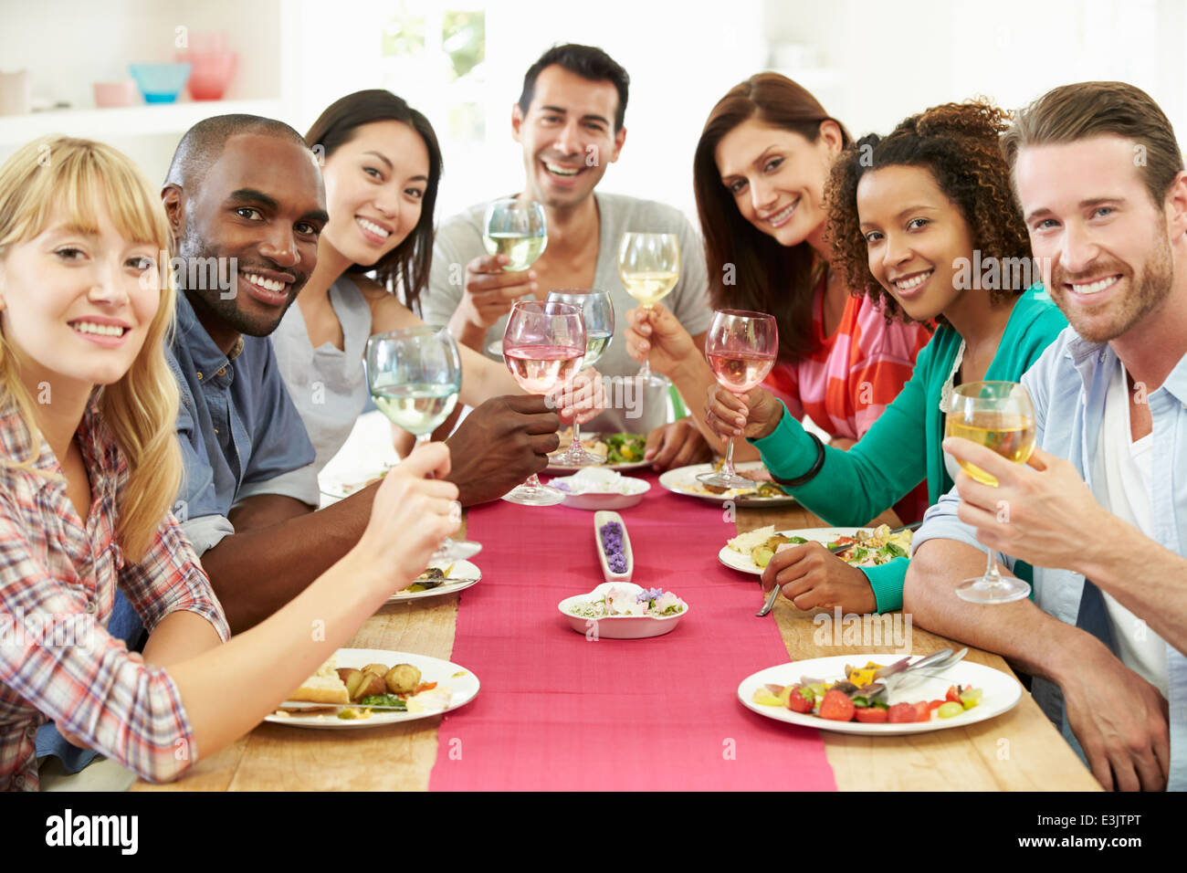 Group Of Friends Sitting Around Table Having Dinner Party Stock Photo