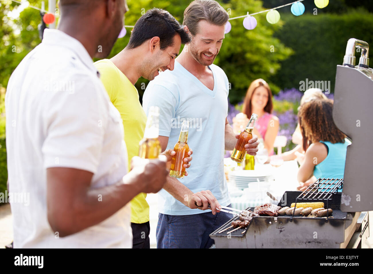 Group Of Men Cooking On Barbeque At Home Stock Photo