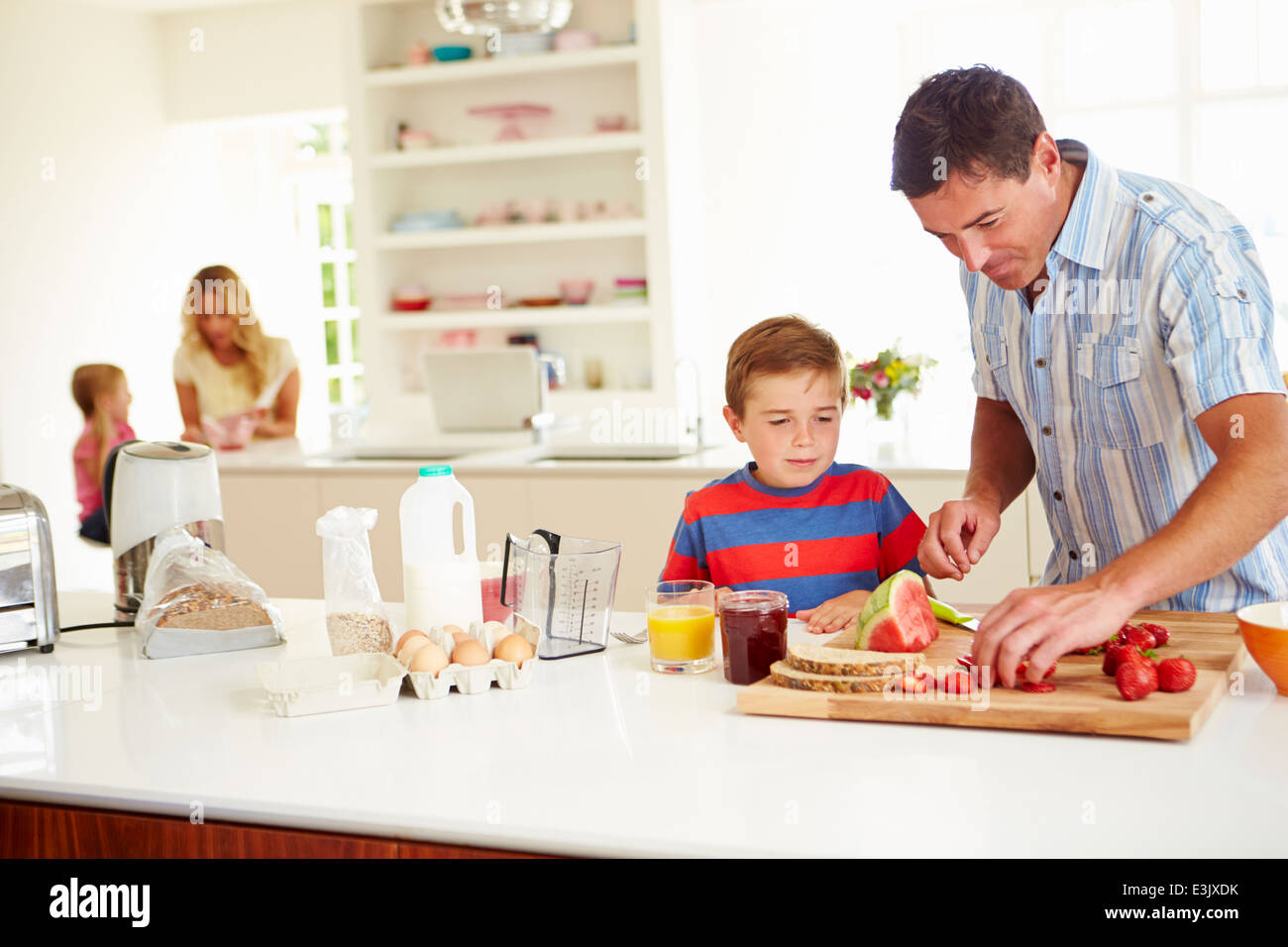 Son Helping Father To Prepare Family Breakfast In Kitchen Stock Photo