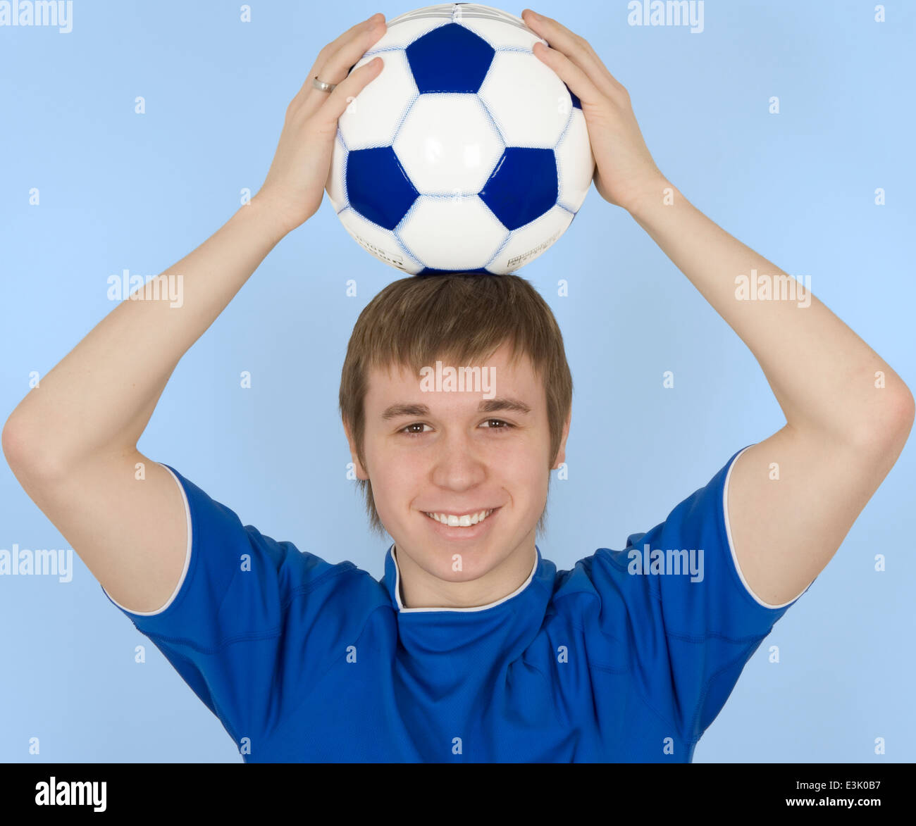 Young man holding soccer ball on head, smiling, portrait Stock Photo