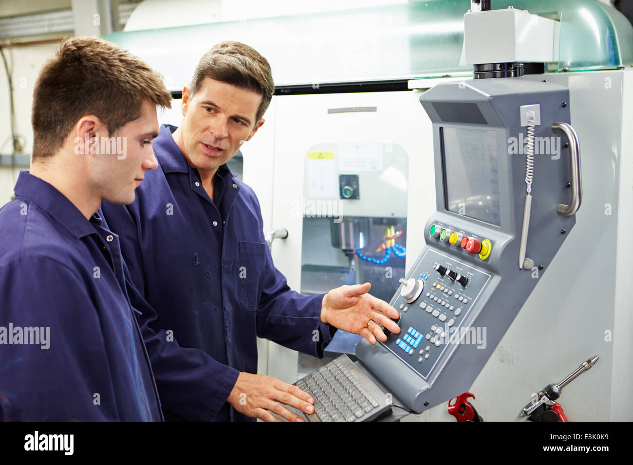Engineer And Apprentice Using Automated Milling Machine Stock Photo