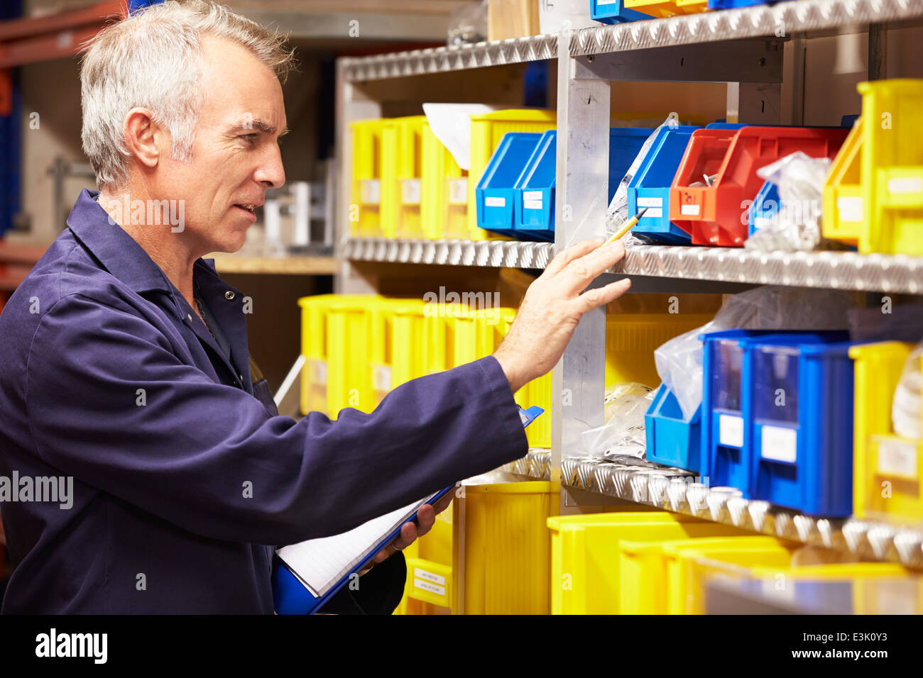 Worker Checking Stock Levels In Store Room Stock Photo