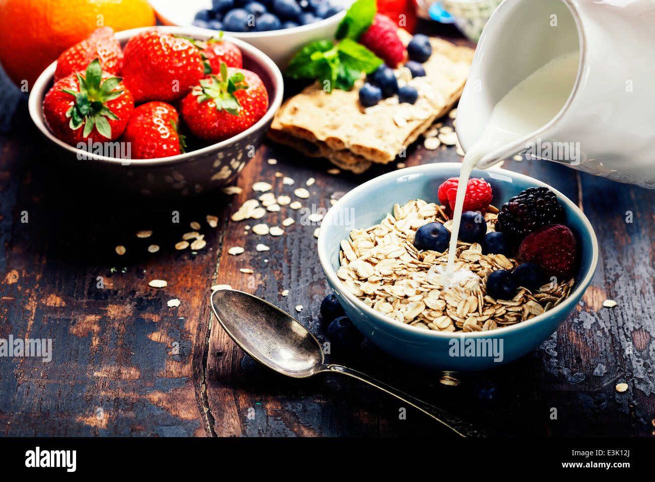 diet breakfast - bowls of oat flake, berries and fresh milk on wooden background - health and diet concept Stock Photo