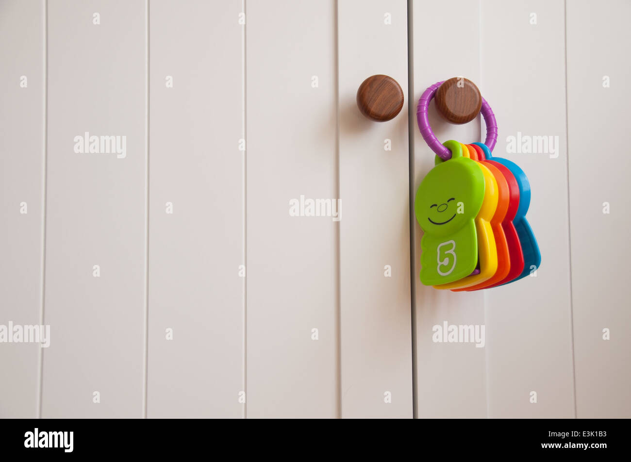 Babies toy hanging on a white wardrobe door in a nursery Stock Photo