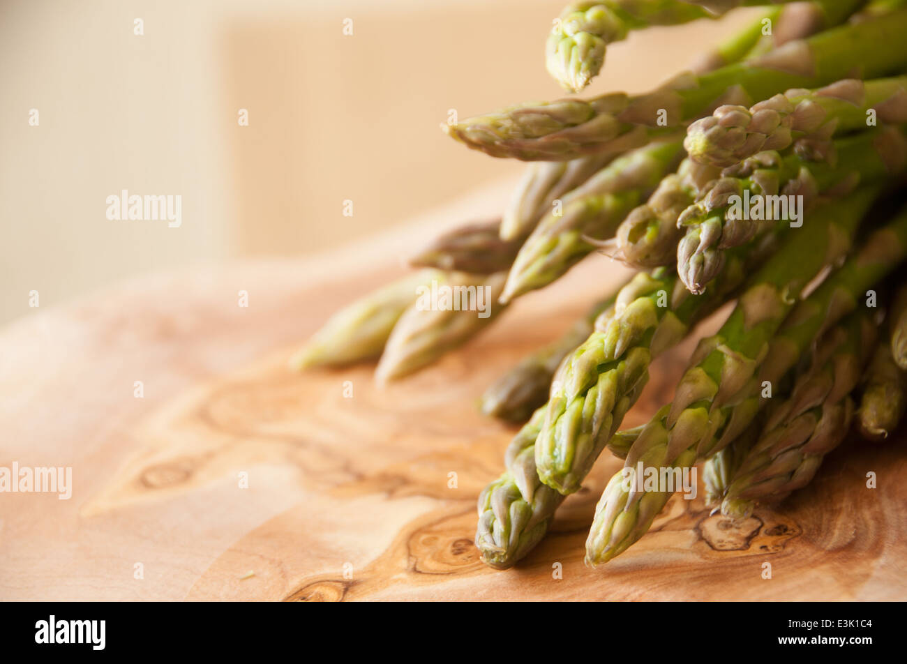 Fresh organic asparagus bunched together on a wooden chopping board Stock Photo