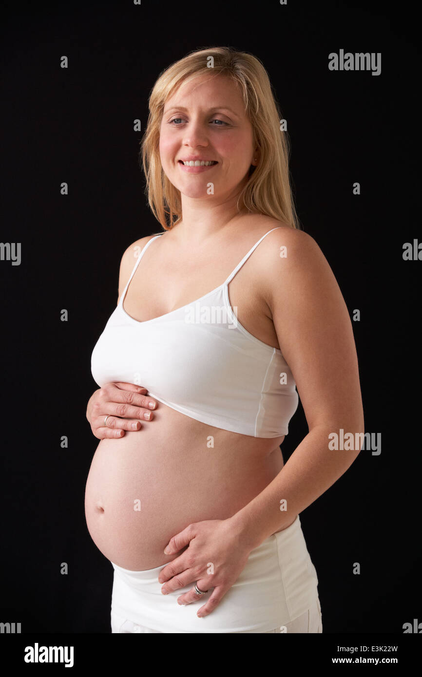 Portrait Of Pregnant Woman Wearing White On Black Background Stock Photo