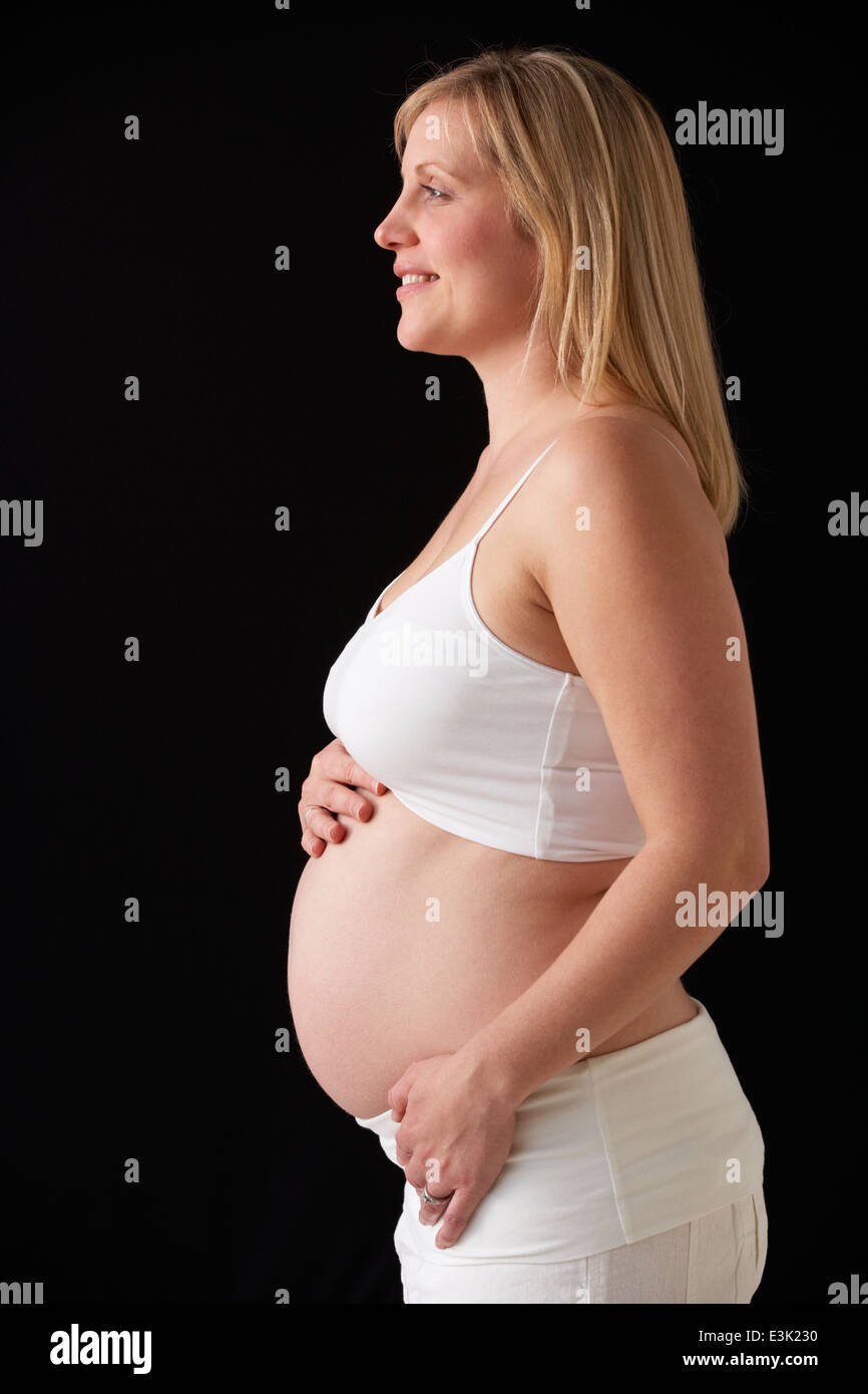 Portrait Of Pregnant Woman Wearing White On Black Background Stock Photo
