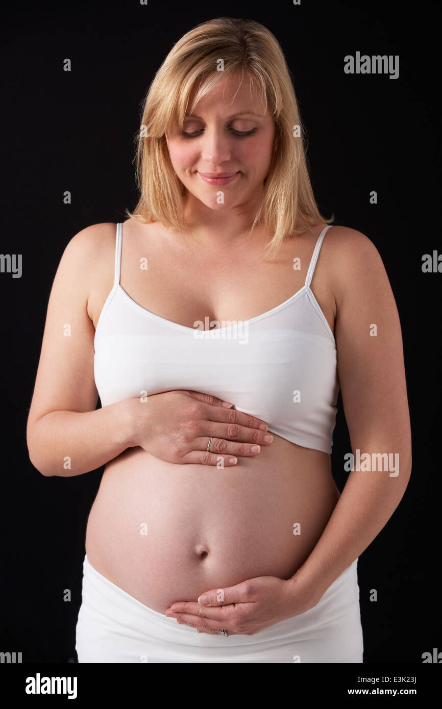 Portrait Of Pregnant Woman Wearing White On Black Background Stock Photo