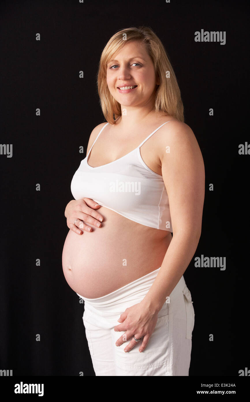 Portrait Of Pregnant Woman Wearing White On Black Background Stock Photo