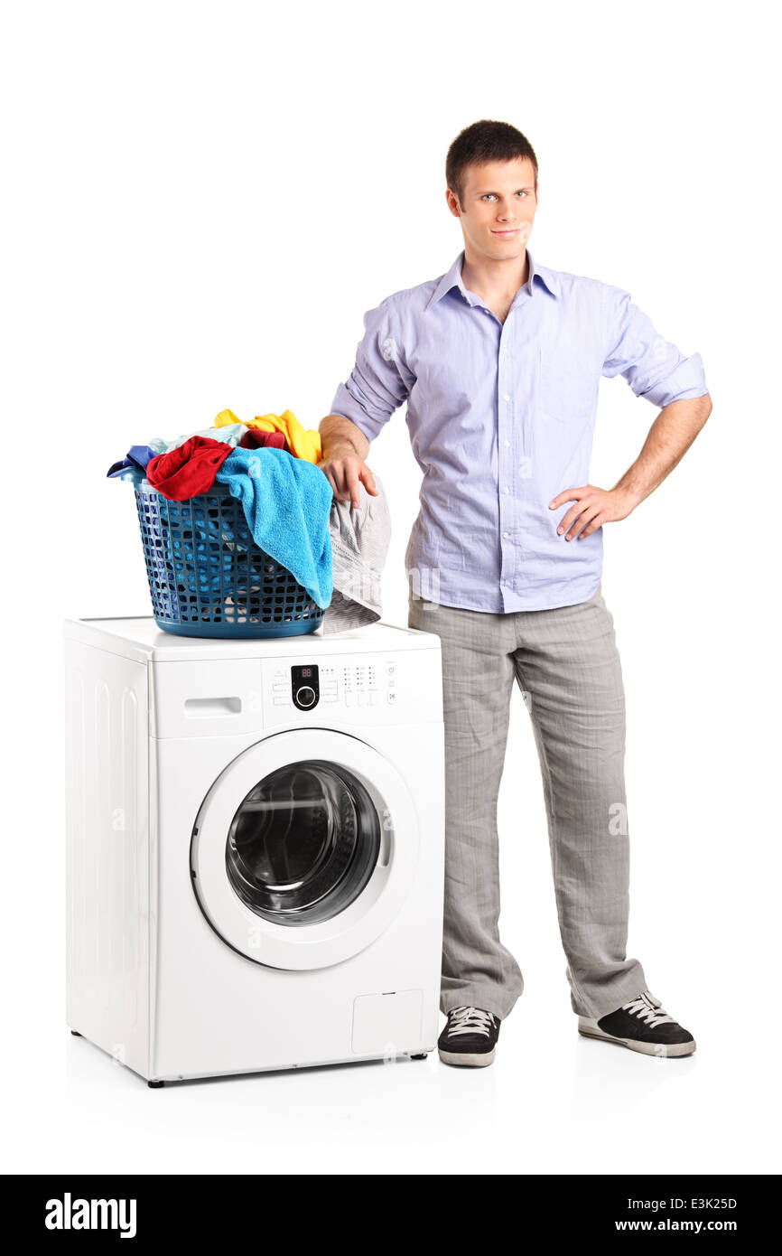 Full length portrait of a guy standing by a washing machine with a laundry basket on it Stock Photo