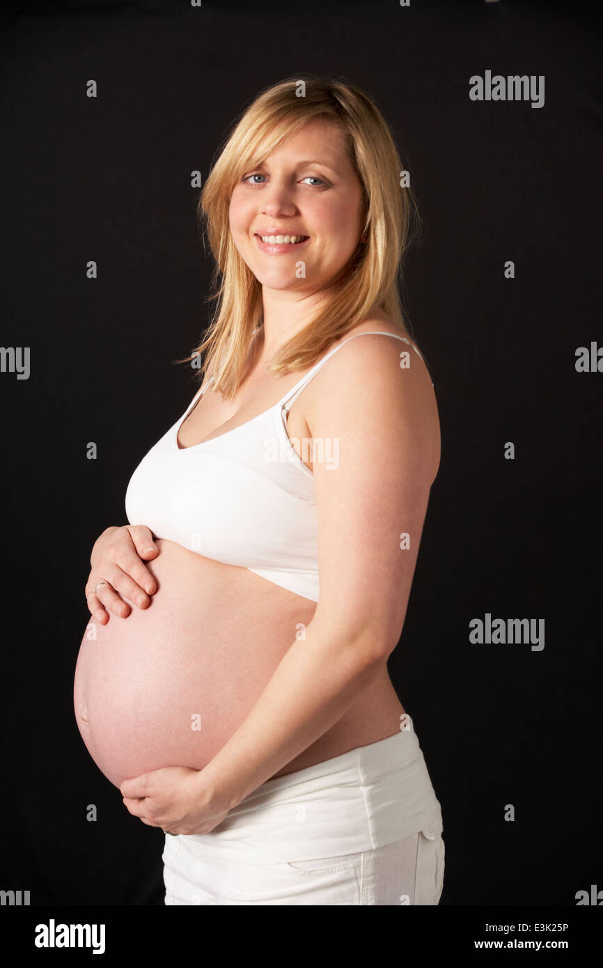 Portrait Of Pregnant Woman Wearing White On Black Background Stock Photo