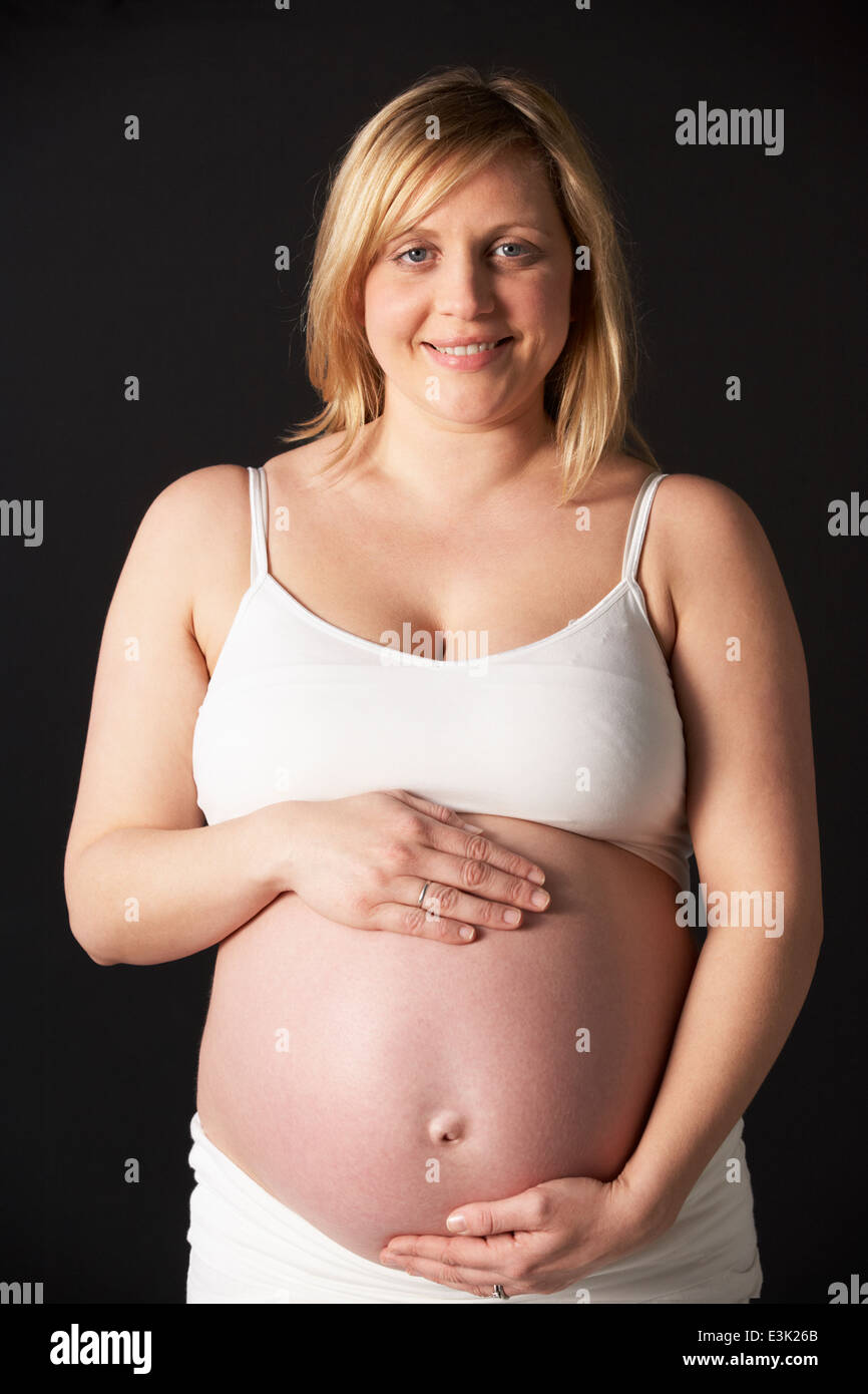 Portrait Of Pregnant Woman Wearing White On Black Background Stock Photo