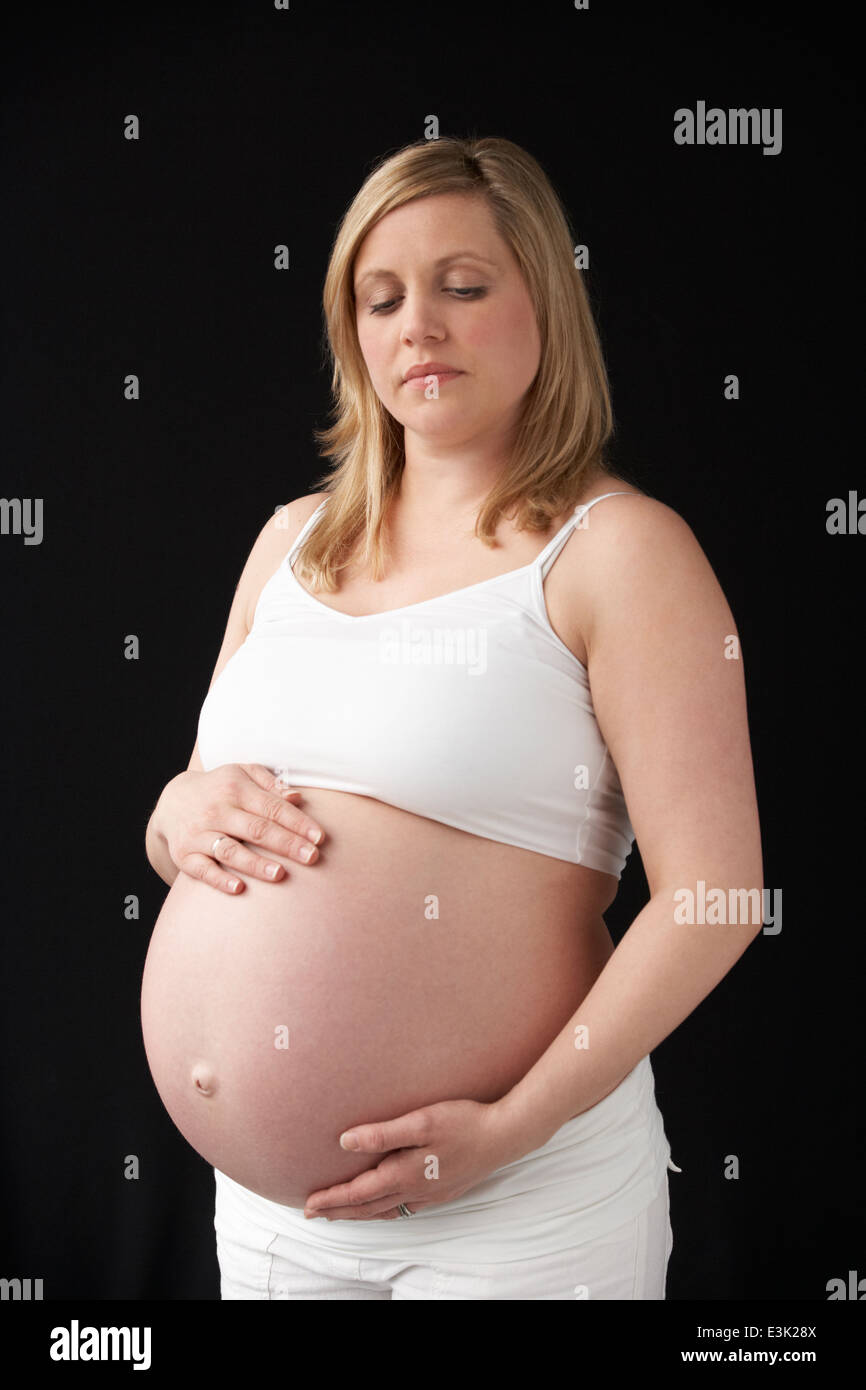 Portrait Of Pregnant Woman Wearing White On Black Background Stock Photo
