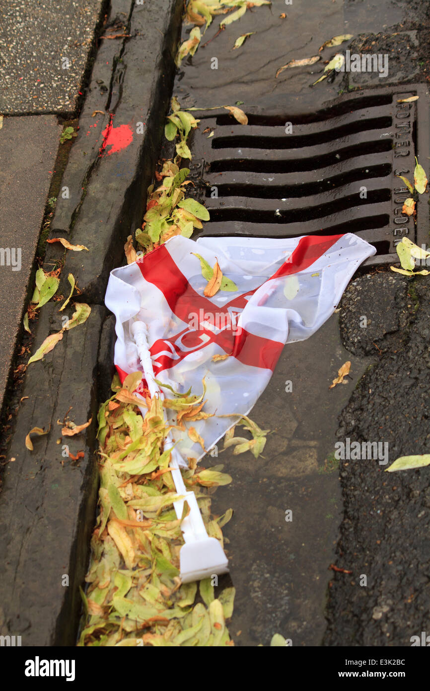 England football team flag going down the drain. England football team flag in the gutter among leaves and debris. Stock Photo