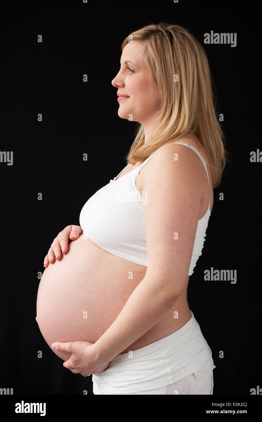 Portrait Of Pregnant Woman Wearing White On Black Background Stock Photo