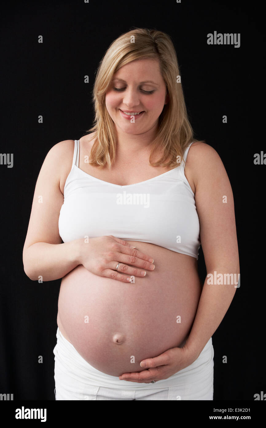 Portrait Of Pregnant Woman Wearing White On Black Background Stock Photo