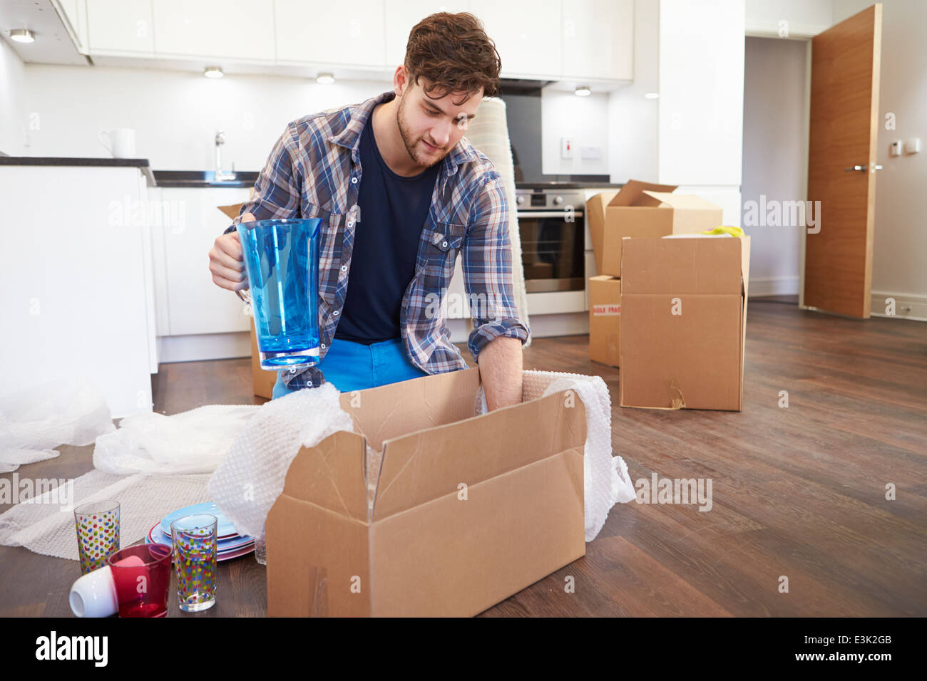Man Moving Into New Home And Unpacking Boxes Stock Photo