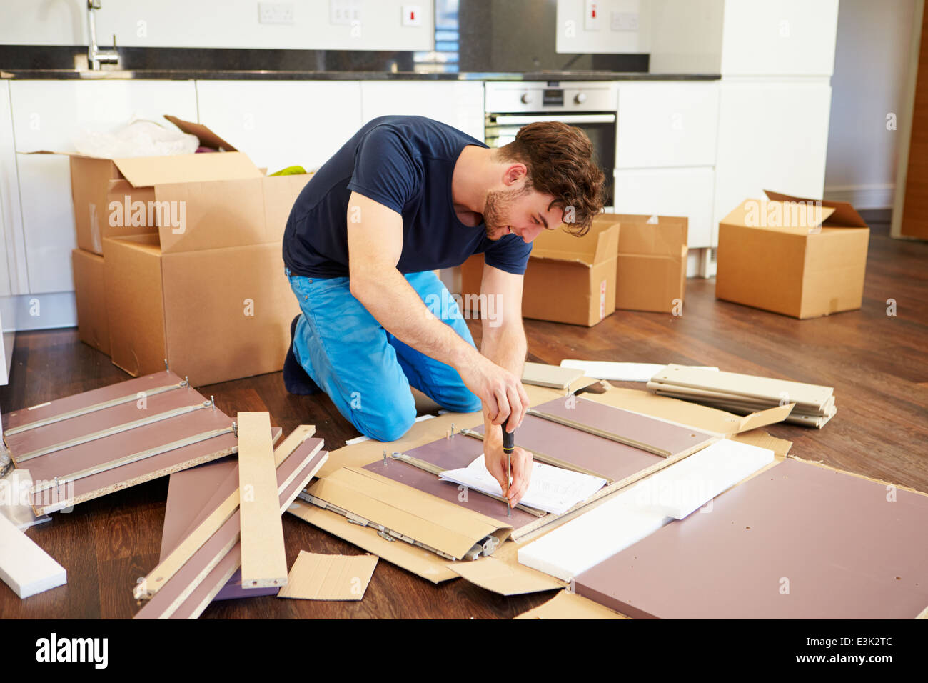 Man Putting Together Self Assembly Furniture In New Home Stock Photo
