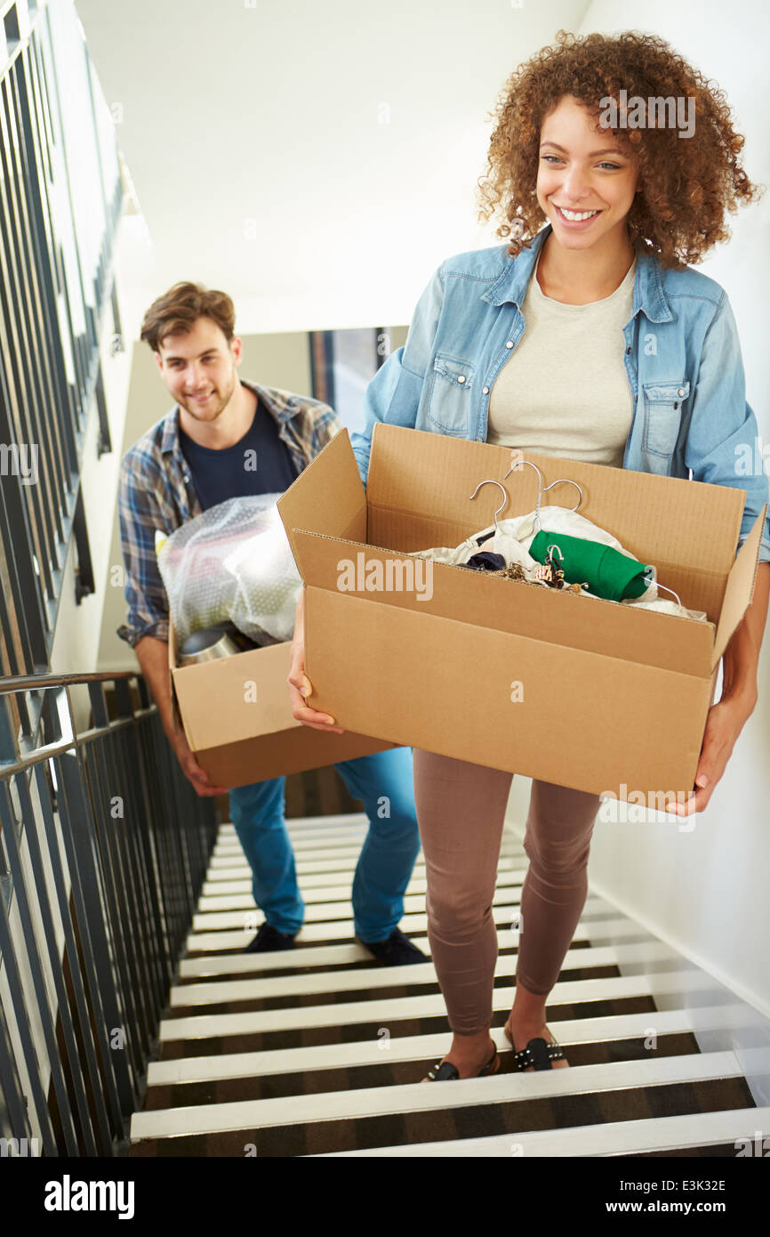 Couple Moving Into New Home Carrying Box Upstairs Stock Photo