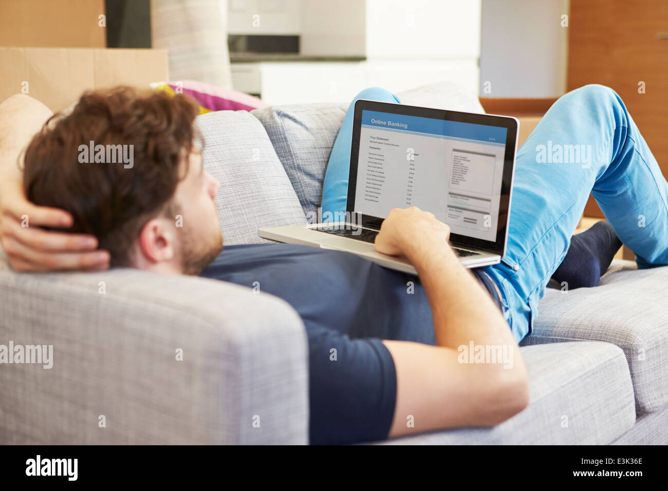 Man Using Online Banking Relaxing On Sofa Stock Photo