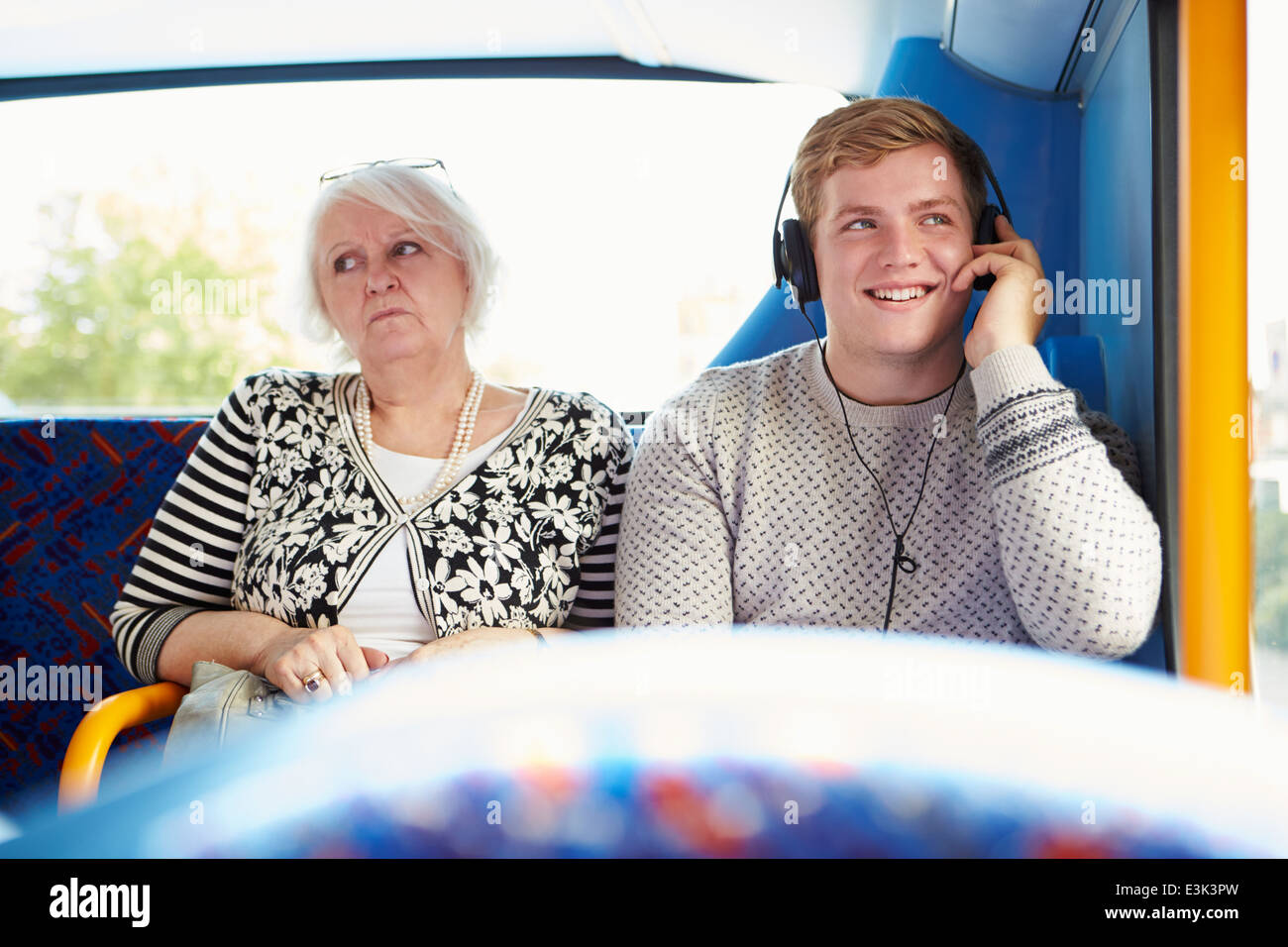 Man Disturbing Passengers On Bus Journey With Loud Music Stock Photo