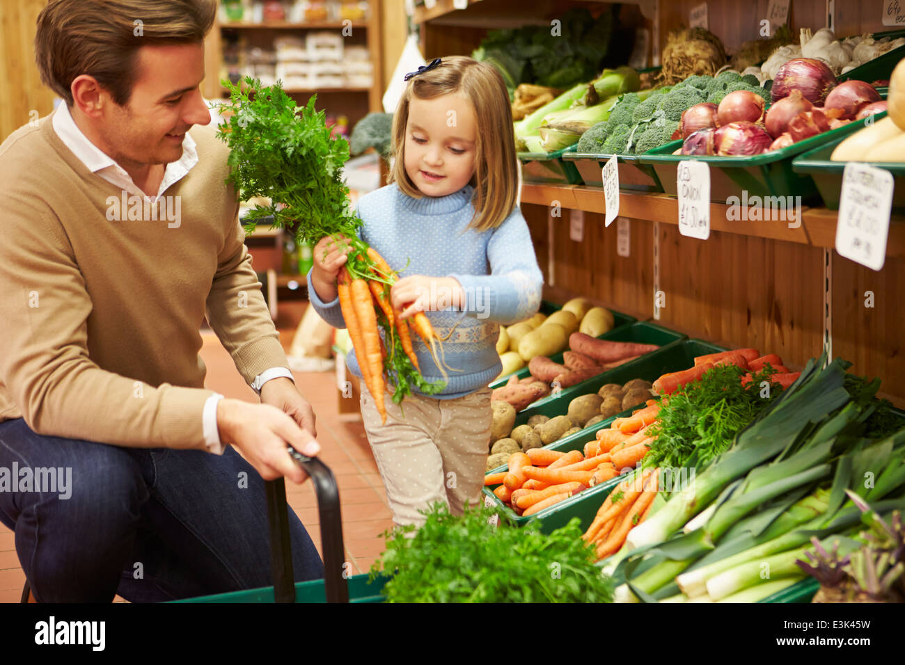 Father And Daughter Choosing Fresh Vegetables In Farm Shop Stock Photo